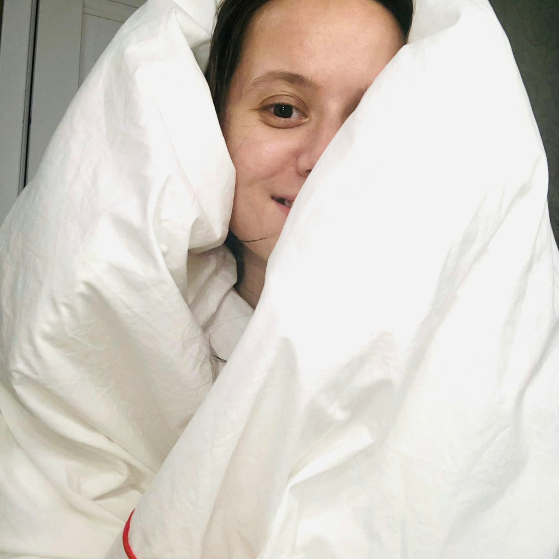 woman lying on bed covered with white blanket