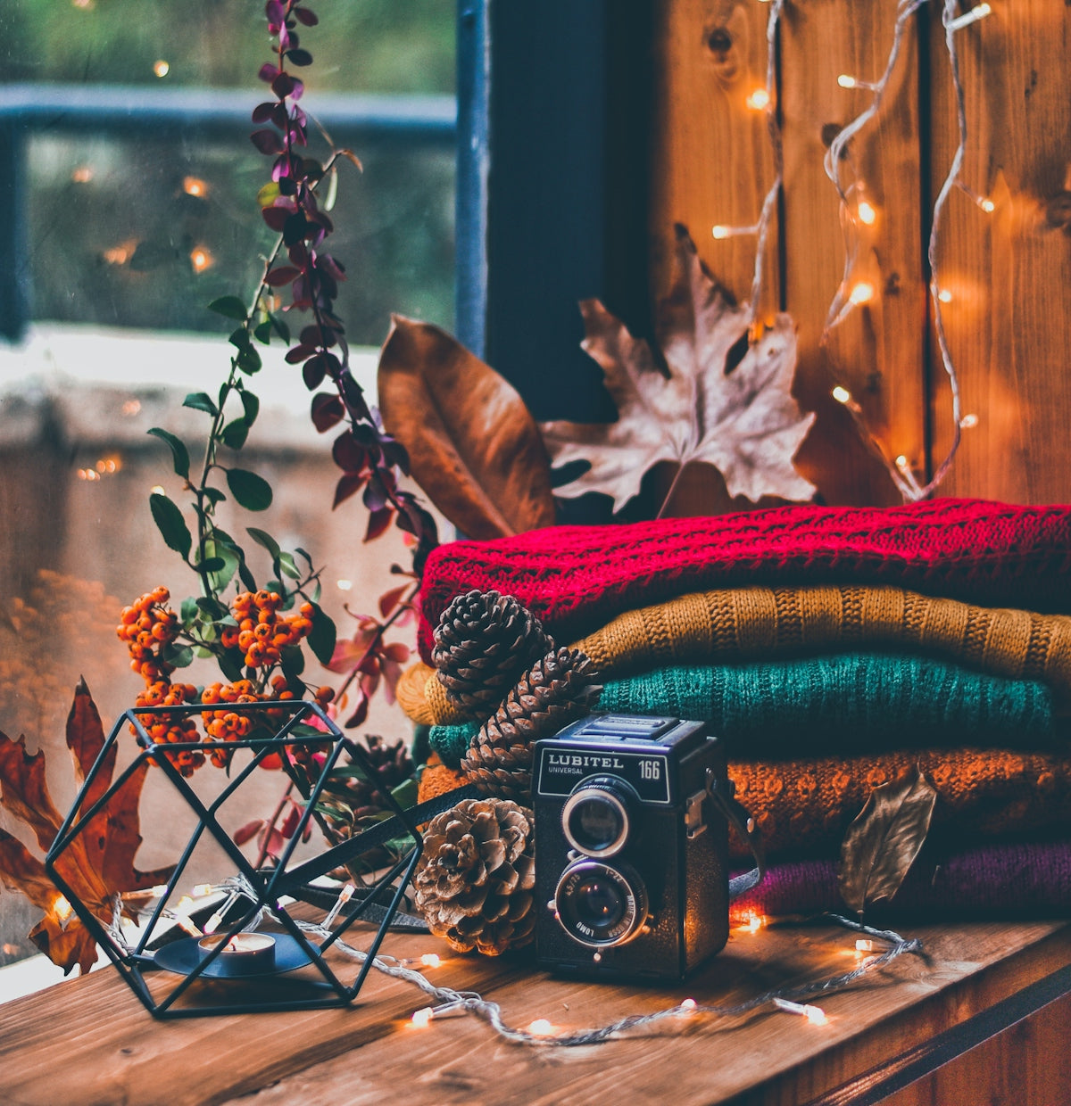 a wooden table topped with a camera and a pile of blankets