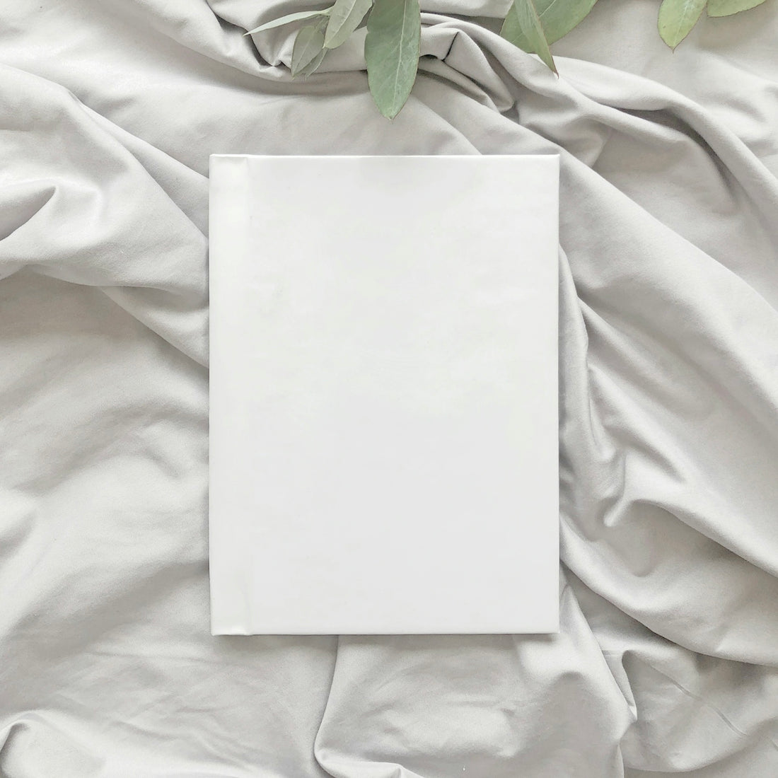 a white sheet of paper on a bed with a plant