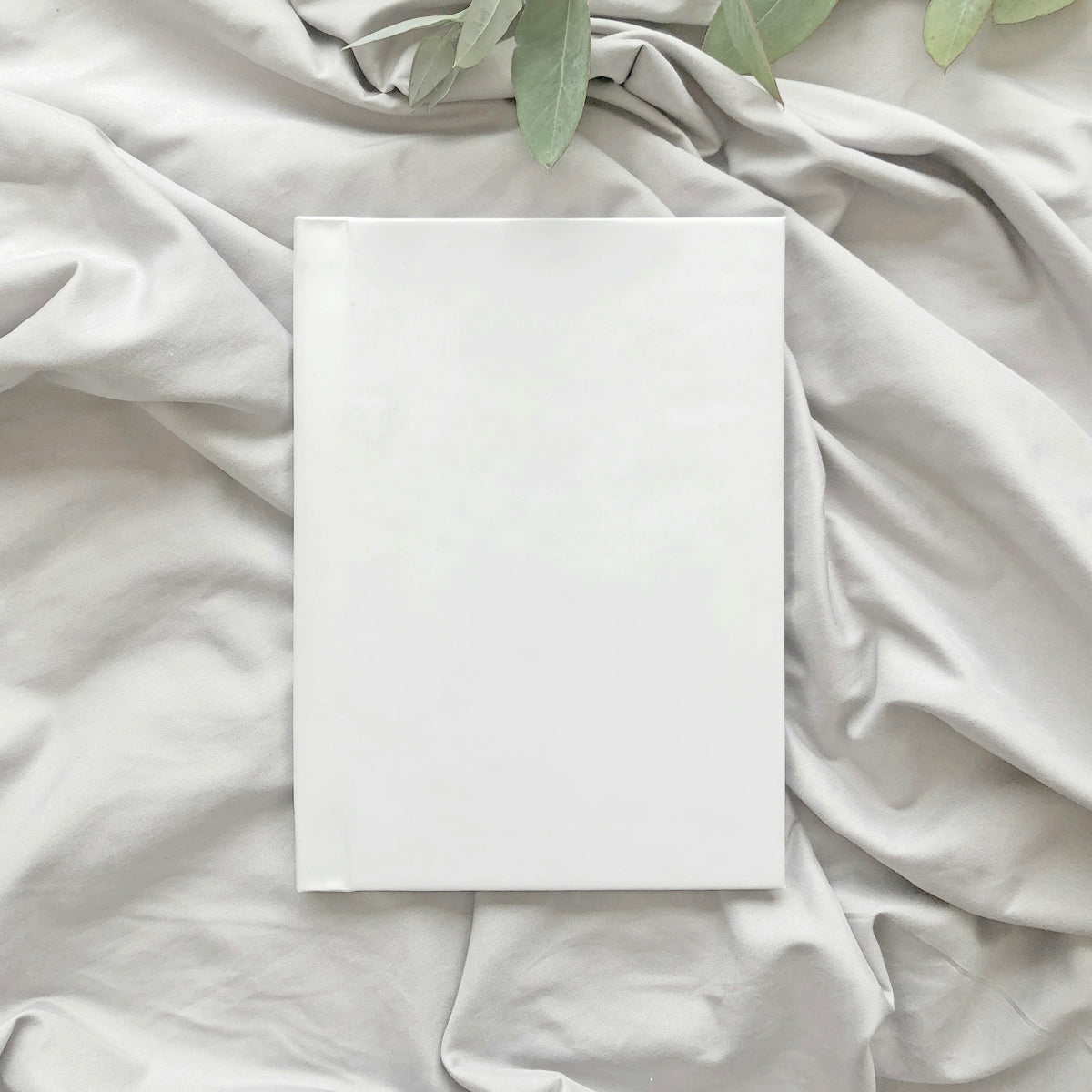 a white sheet of paper on a bed with a plant