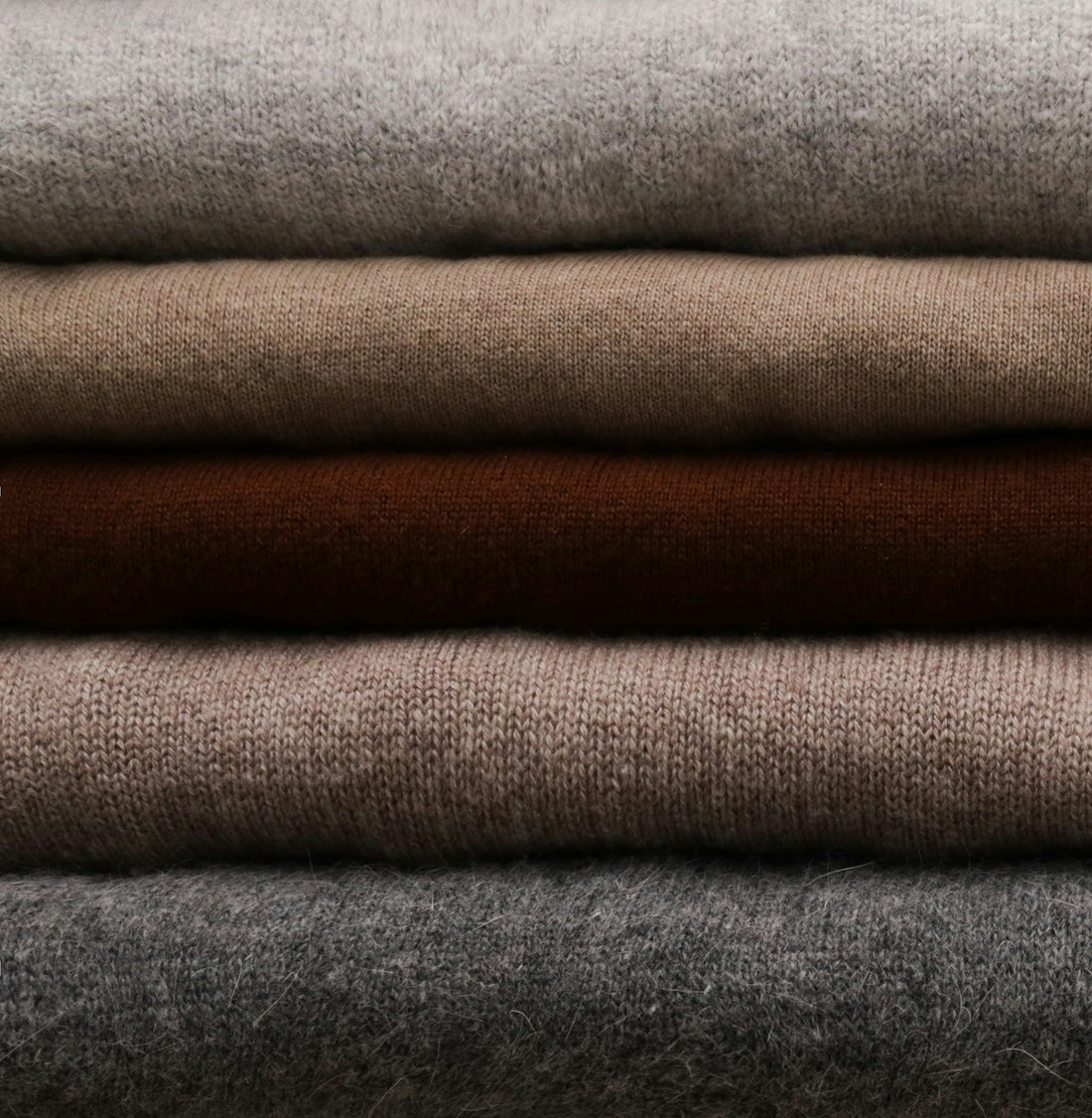 a stack of different colored sweaters sitting on top of each other