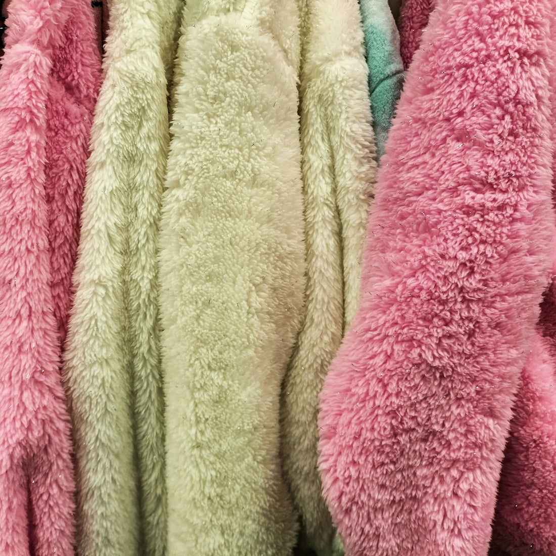 A bunch of pink and white teddy bears hanging on a rack