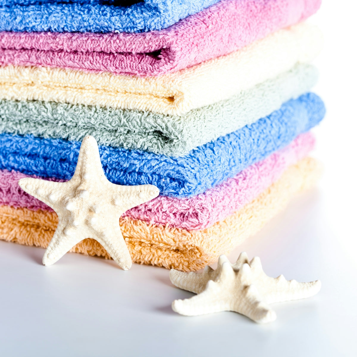 A stack of towels and a starfish on a white background