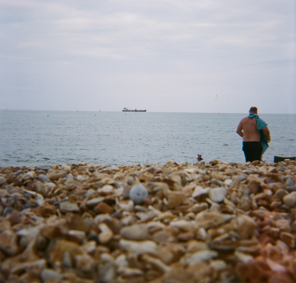 Person on a pebble beach looking at the sea