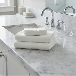 Folded white hand towel in a bathroom near sink