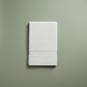 Folded white bath towel on a green background