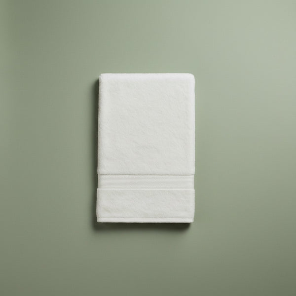 Folded white bath towel on a green background