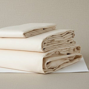 Folded beige bed sheets on a beige background. T-250 | Rifz Textiles