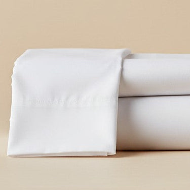 T-250 White Percale Sheets in a Bedroom with neatly made bed, side table, and window with curtains | Rifz Textiles