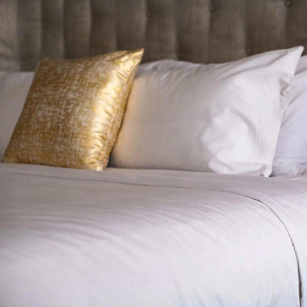 GSD Collection T-300 White Sheets. Neatly made bed in a bright bedroom with wooden floor and large window. Rifz Textiles INC